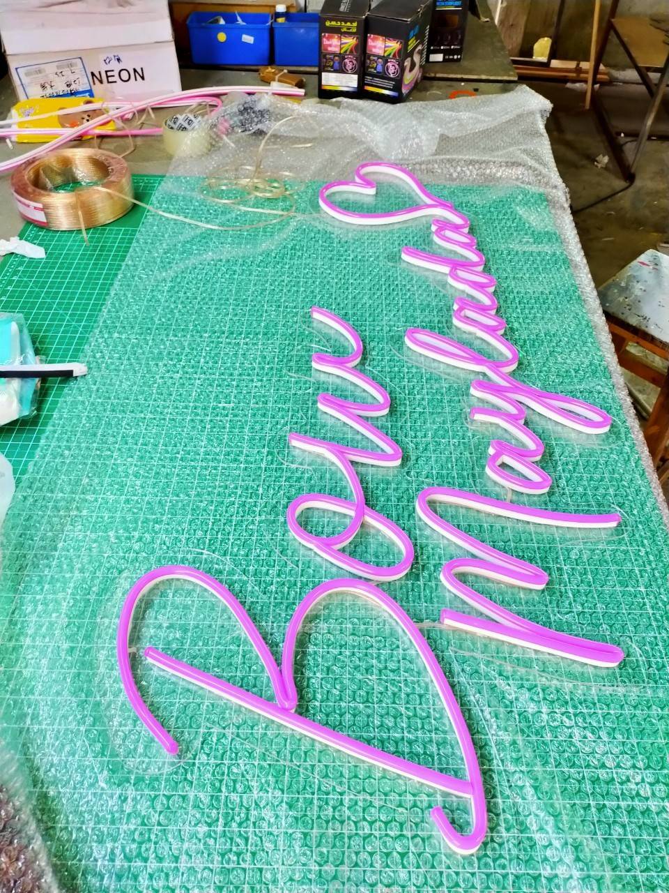 ป้ายไฟนีออนดัด แสงสีชมพู วางหลังอะคริลิคใสไดคัท