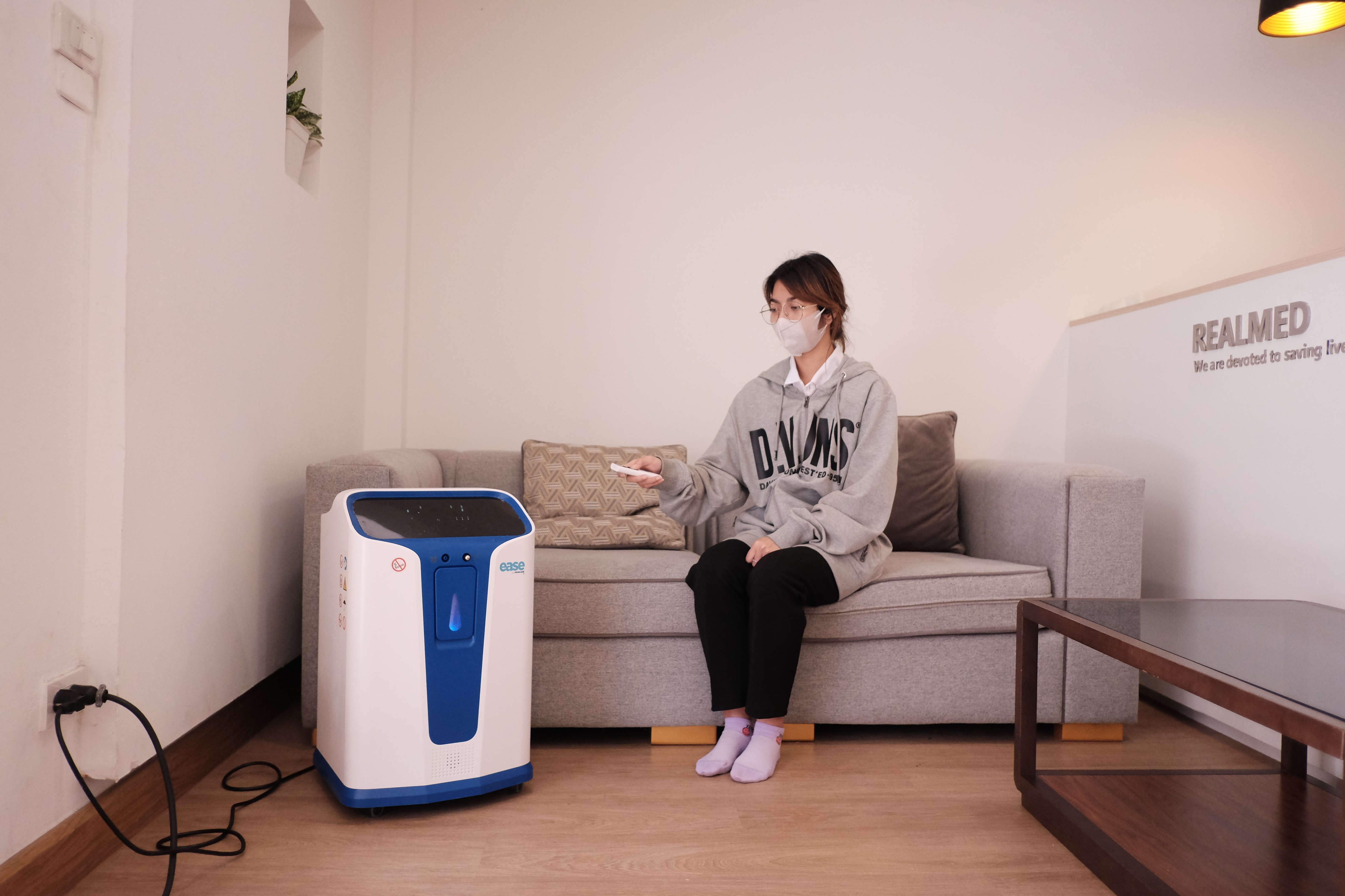 A person sitting on a couch with a device

Description automatically generated